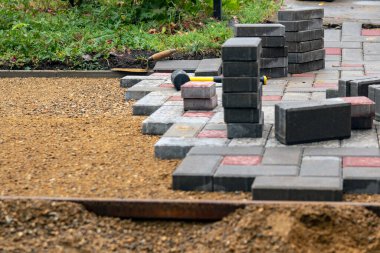 Avlu avlusunda beton döşeme döşeme döşemesi. Profesyonel işçiler düz kumlu bir temele garaj yolu, kaldırım ya da veranda için yeni fayanslar ya da levhalar kuruyorlar.