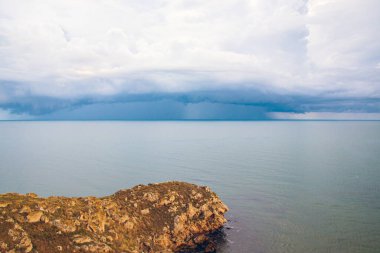  Sabahın erken saatlerinde kumlu plajlı kayalıklarla kıyı şeridi. Karanlık fırtına bulutları ve sakin denizle sonbahar havası