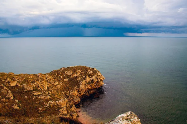  Şafaktan önce dramatik bir gökyüzü, denizde yağan yağmur sırasında destansı çok renkli bulutlar. Seyahat ve turizm, ekoloji teması