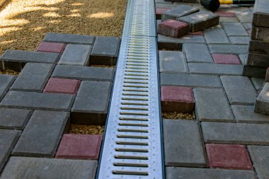 Profesyonel tuğla ustaları yol, kaldırım ya da veranda için yeni kiremitler ya da levhalar döşüyorlar. Evin avlusuna gri beton döşeme döşemesi.
