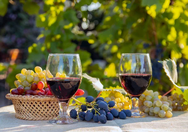 An assortment of fresh grapes and a glass of wine on the table and in the basket. Selective focus