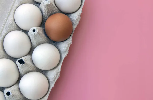 chicken eggs in an egg box and egg yolk on a pink background. copy space. The concept of natural healthy nutrition and organic farming. Boxing egg