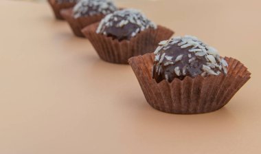 Hindistan cevizli minyon dörtlü, hindistan cevizli ve üzeri hindistan cevizli sulu çikolatalı kek. Bej arka planda mini kek. Seçici odaklanma. Metin için yer