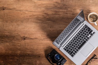 Modern dizüstü, kahve ve bir eski analog fotoğraf makinesi masanın köşesinde yalan. Fotoğraf boşaltmak içerir