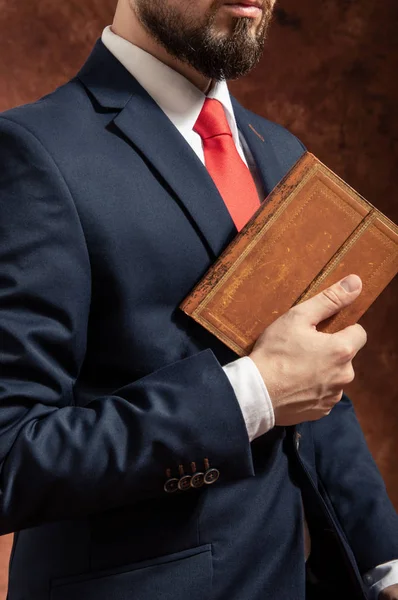 Man in suit stands with old vintage book