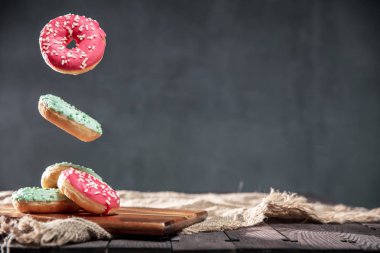 Çörek sprinkles ile boşaltmak metniniz için rustik masa üzerine pembe ve yeşil buzlanma ile. Fotoğrafın yatay yönlendirme.