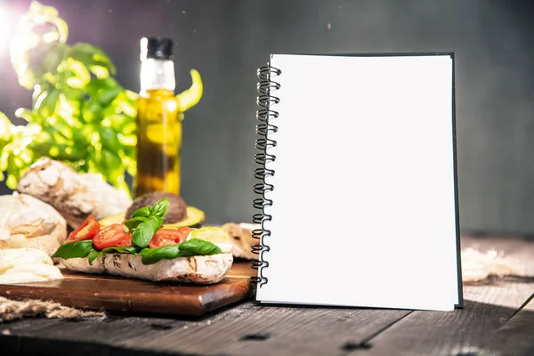 チャバタのパン アボカド トマト モッツァレラチーズ オリーブ オイル バジル テキストの Copyspace のノートを持つ素朴なテーブル — ストック写真