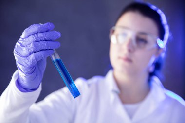 Mavi sıvı ile test tüpü tutan ecza el. Yatay görünüm