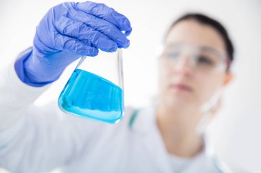 Kimyager mavi sıvı balonun içinde bakar. Yatay görünüm