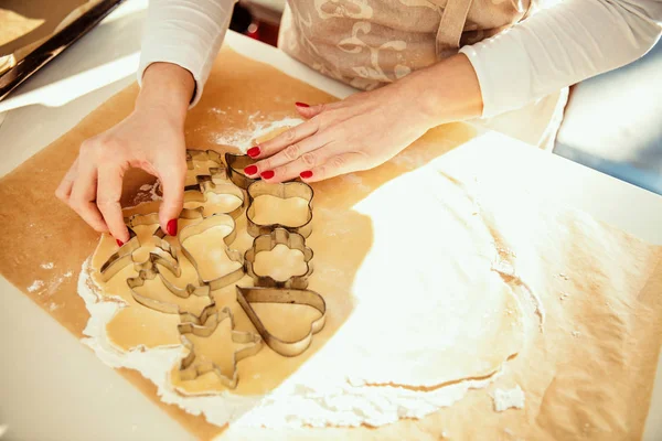 Woman cuts off the dough for homemade cookies with cake cutting molds.