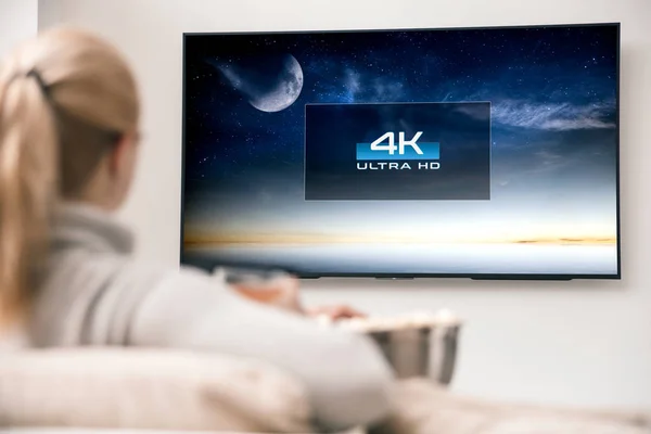 Femme regarde la télévision avec une résolution ultra HD 8k . Photos De Stock Libres De Droits