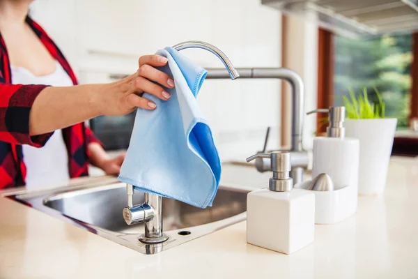 Kvinnan torkar handfatet med blått tyg i köket. — Stockfoto