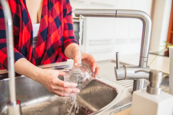 女は台所で水でガラスをすすいでいる. — ストック写真