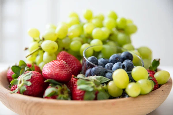 Cuenco de madera con frutas: fresas, arándanos y gra verde —  Fotos de Stock