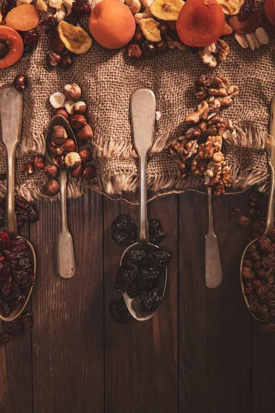 Frutas secas y frutos secos dispuestos en una cuchara, tela y una mesa vieja — Foto de Stock