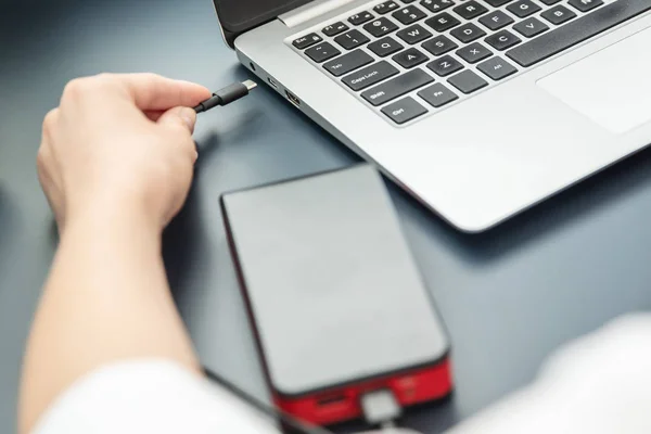 Frau lädt ihren Laptop mittels USB-C-Kabel mit Powerbank auf. — Stockfoto