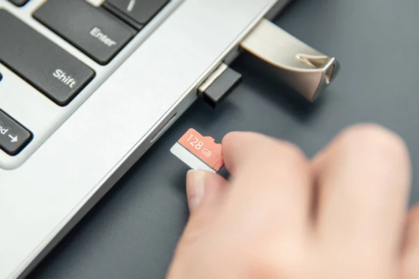 Frauenhand legt schnelle, kapazitätsstarke Mikroskopkarte ins moderne Ultrabook. — Stockfoto