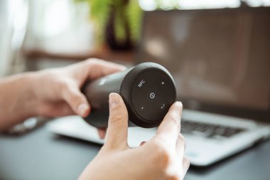 Kadın eller kablosuz bir hoparlör tutuyor.