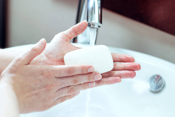 Washing hands. Female hands are being washed with soap in the sink