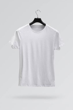 Beyaz arka planda izole edilmiş bir askıda beyaz erkek pamuk tişörtünün ön tarafı. Parmak izi olmayan tişört