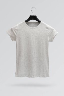 Gri arka planda izole edilmiş bir askıda kadın gri melanj pamuk tişörtünün ön tarafı. Parmak izi olmayan tişört.