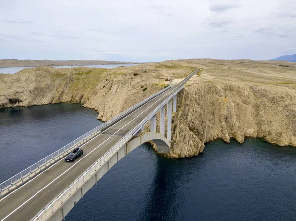 Aerial view of the bridge of the island of Pag, Croatia, roads and Croatian coast. Cliff overlooking the sea. Cars crossing the bridge seen from above