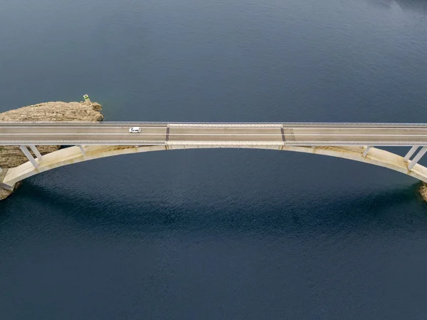 Aerial view of the bridge of the island of Pag, Croatia, road. Cliff overlooking the sea. Cars crossing the bridge seen from above