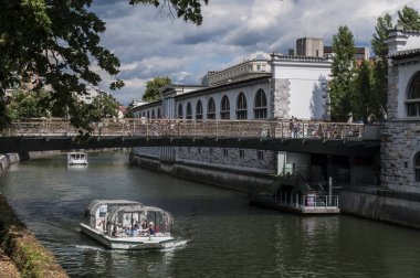 Slovenya, 24/06/2018: Ljubljana, şehir, Orta Çağ'kasap köprünün altından Ljubija olarak bilinen Ljubljanica Nehri üzerinde seyir bir turist teknesi ile şehrin manzarası