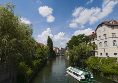 Slovenya, 24/06/2018: Ljubljana, şehir, Orta Çağ'Ljubija bilinen Ljubljanica Nehri'nin üzerinde seyir bir turist teknesi ile şehrin siluetinin görünümü