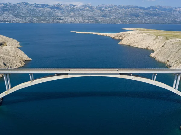 Aerial view of the bridge of the island of Pag, Croatia, road. Cliff overlooking the sea. Cars crossing the bridge seen from above