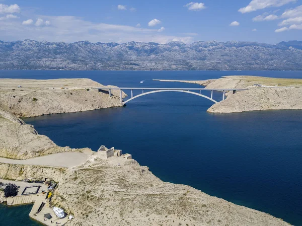 Aerial view of the bridge of the island of Pag, Croatia. Ruins of ancient Fortress Fortica on Pag Island, Croatia. Cars crossing the bridge seen from above