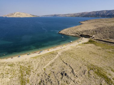 Hırvatistan 'ın Metajna kentindeki Pag Adası' ndaki Rucica plajının hava manzarası. Deniz yatağı ve plaj yukarıdan görünüyor, banyolar, rahatlama ve yaz tatilleri. Hırvat kıyılarının önyargıları ve uçurumları