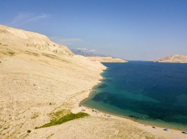 Hırvatistan 'ın Metajna kentindeki Pag Adası' ndaki Rucica plajının hava manzarası. Deniz yatağı ve plaj yukarıdan görünüyor, banyolar, rahatlama ve yaz tatilleri. Hırvat kıyılarının önyargıları ve uçurumları