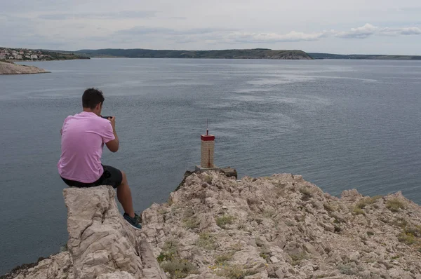 クロアチア 2018 荒天および Paski のほとんどは 主要な土地とパグ島を結ぶ 1968年橋の前に崖の上少し赤い灯台の写真を撮る男 — ストック写真