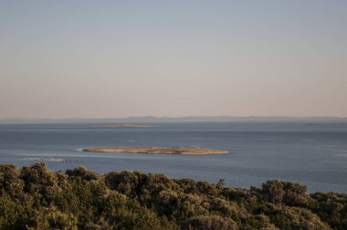 Hırvatistan, 30/06/2018: Akdeniz maki ve Gajac, Kuzey Adriyatik Denizi Pag Island üzerinde uzak küçük bir köy yakınındaki küçük bir ada gün batımında görünümü