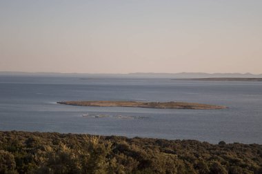 Hırvatistan, 30/06/2018: Akdeniz maki ve Gajac, Kuzey Adriyatik Denizi Pag Island üzerinde uzak küçük bir köy yakınındaki küçük bir ada gün batımında görünümü