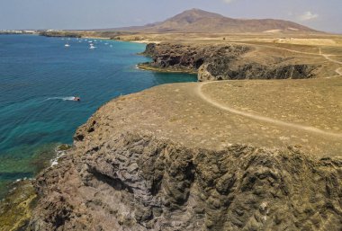 Lanzarote, İspanya ve Kanarya 'nın sivri kıyılarının havadan görünüşü. Yollar ve toprak yollar. Adayı keşfetmek için yürüyüş rotaları. Kumsalda yüzüyor. Atlantik Okyanusu. Papagayo