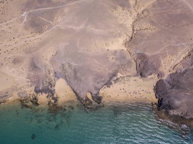 Lanzarote, İspanya ve Kanarya 'nın sivri kıyılarının havadan görünüşü. Yollar ve toprak yollar. Adayı keşfetmek için yürüyüş rotaları. Kumsalda yüzüyor. Atlantik Okyanusu. Papagayo