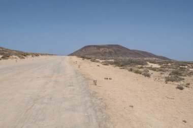 Lanzarote, Kanarya Adaları, 12/09/2018: toprak yol, bush ve desertic yatay olarak Montana Pedro Barba, ikiz-summitted ve ikiz krateri volkan La Graciosa, ana adalar ada Chinijo