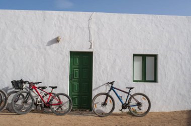 Canary Islands, 12/09/2018: bicycles on the wall of a white house in Caleta de Sebo, the main village of La Graciosa, the archipelago island Chinijo, a group of little islands northwest of Lanzarote clipart