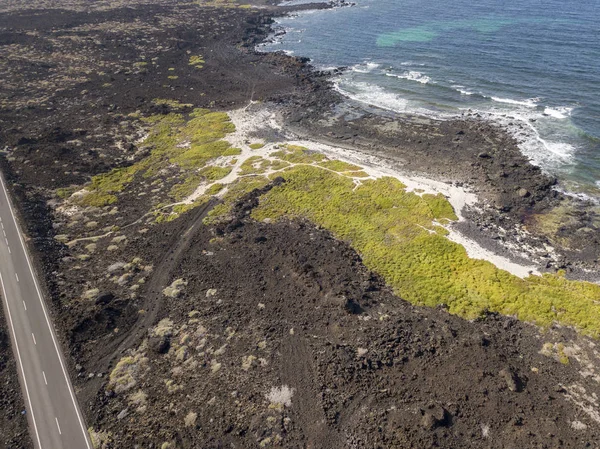 Aerial view of a road that runs through lava fields between the indented coastline of Lanzarote, Canary Islands, Spain, Africa. Wild nature.