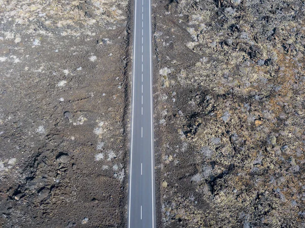 Aerial view of a road that runs through lava fields of Lanzarote, Canary Islands, Spain, Africa. Wild nature