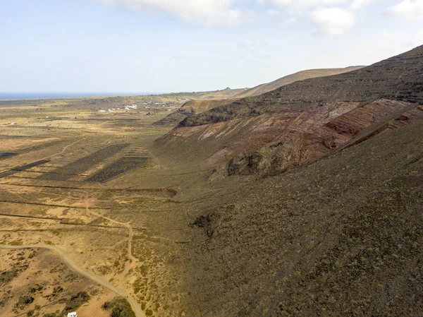 Aerial view of a parking camper surrounded by mountains of the island of Lanzarote, Canary Islands, Spain. Africa. Reliefs overlooking the sea and dirt paths. Hiking trails