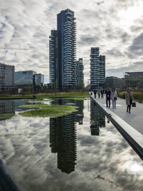 Ağaçlar, yeni Milan park Kütüphanesi. Solaryum panelleri tower. 11/07/2018. Gökdelenlerin panoramik manzaralı yolları Park. Çeşme yansıtılmış gökdelenler. Lombardy, İtalya