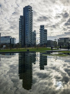 Ağaçlar, yeni Milan park Kütüphanesi. Solaryum panelleri tower. 11/07/2018. Gökdelenlerin panoramik manzaralı yolları Park. Çeşme yansıtılmış gökdelenler. Lombardy, İtalya