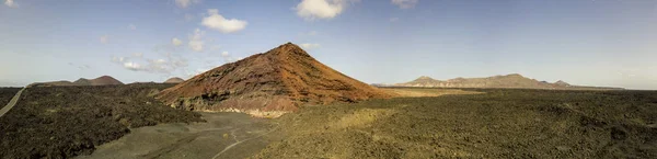 在强烈的红色 熔岩场包围的 Bermeja 山的鸟图 沿海道路流经黑色的熔岩场 西班牙加那利群岛兰萨罗特岛 — 图库照片
