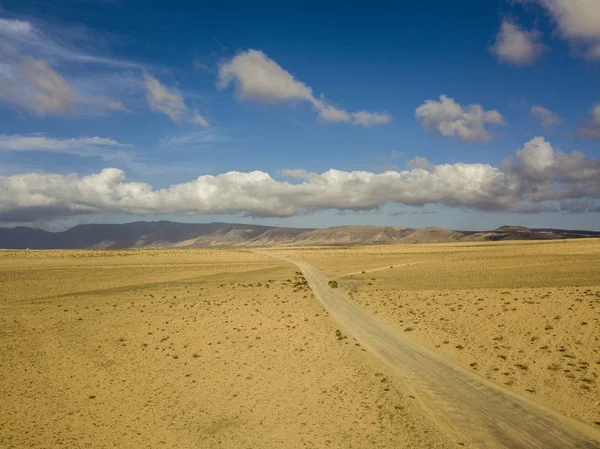 Aerial view of a desert landscape on the island of Lanzarote, Canary Islands, Spain. Road that crosses a desert. Reliefs on the horizon. Volcanoes.