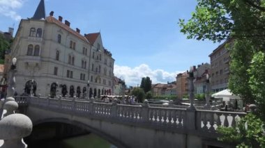 Tromostovje, üçlü köprü Ljubljana Ljubljanica, şehir merkezinde nehrinde. Slovenya 06/26/2018. İnsanlar şehrin trafiğe kapalı alanında geziniyor. Kiliseler ve tepe üzerinde kale