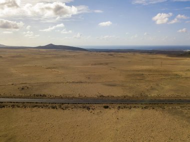 Üzerinde Adası Lanzarote, Kanarya Adaları, İspanya'nın havadan görünümü ıssız bir manzara. Bir çöl geçen yol. Dil siyah asfalt bir çöl kara kesme. Kabartmaları ufukta. Volkanlar.