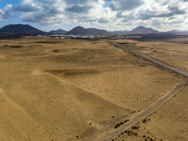 Üzerinde Adası Lanzarote, Kanarya Adaları, İspanya'nın havadan görünümü ıssız bir manzara. Bir çöl geçen yol. Dil siyah asfalt bir çöl kara kesme. Kabartmaları ufukta. Volkanlar.